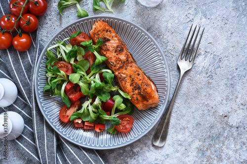 Grilled salmon slice and salad with tomatoes on the kitchen table. Menu for the restaurant.