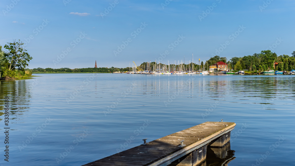 Motor and sail boats anchored on the lake lagoon pier or dock with green river reeds and tries, beautiful summer day on Szczecin yacht marina, Poland