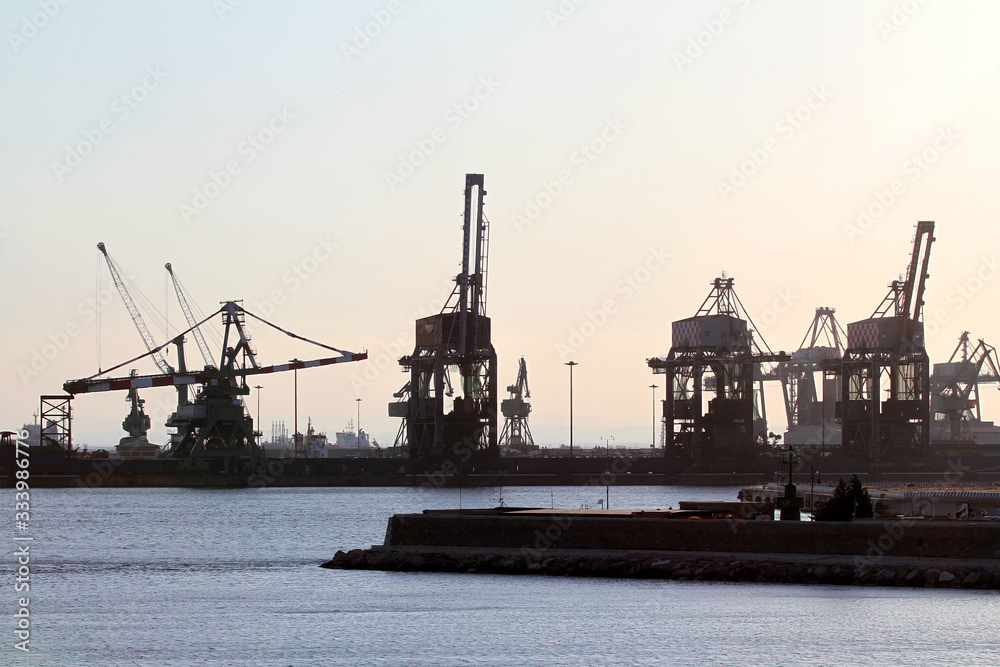 Taranto merchant port at sunset. Silhouette of harbor cranes. Puglia, Italy