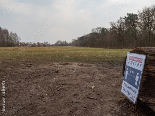 The meadow in Kabacki forest with information about keeping distance due to coronavirus pandemic. photo