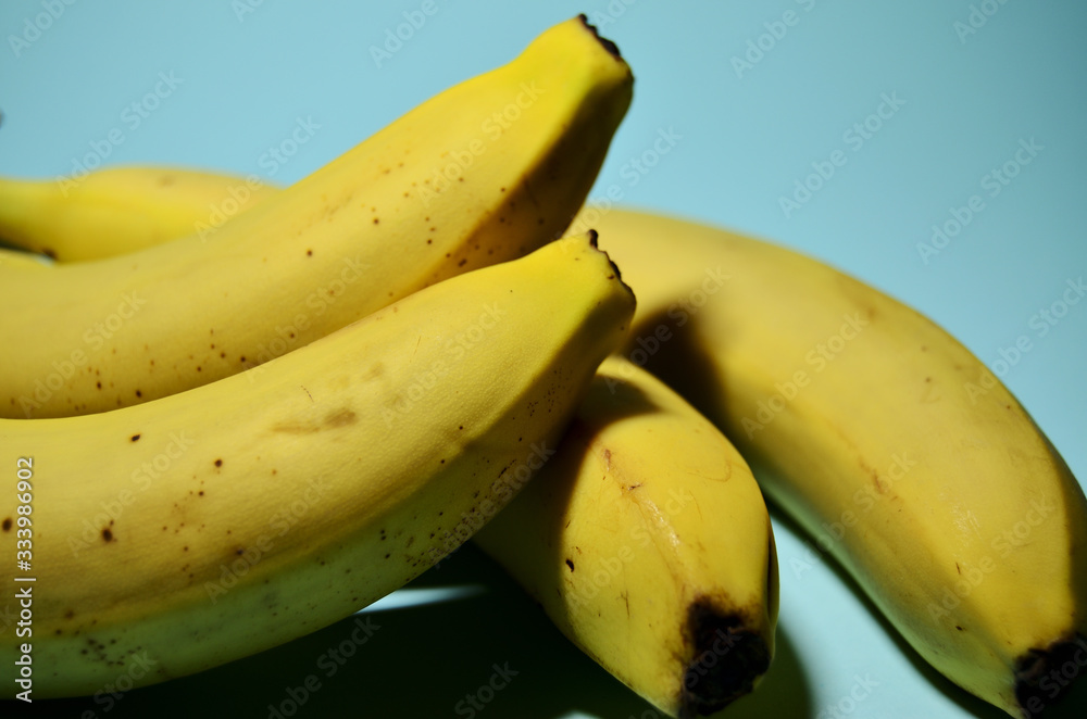 four yellow bananas in a heap on a mint background close-up