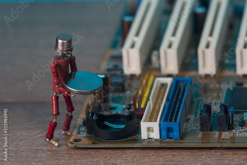 small human figure, made from resistors and transistor, helps to fix electronic computer board