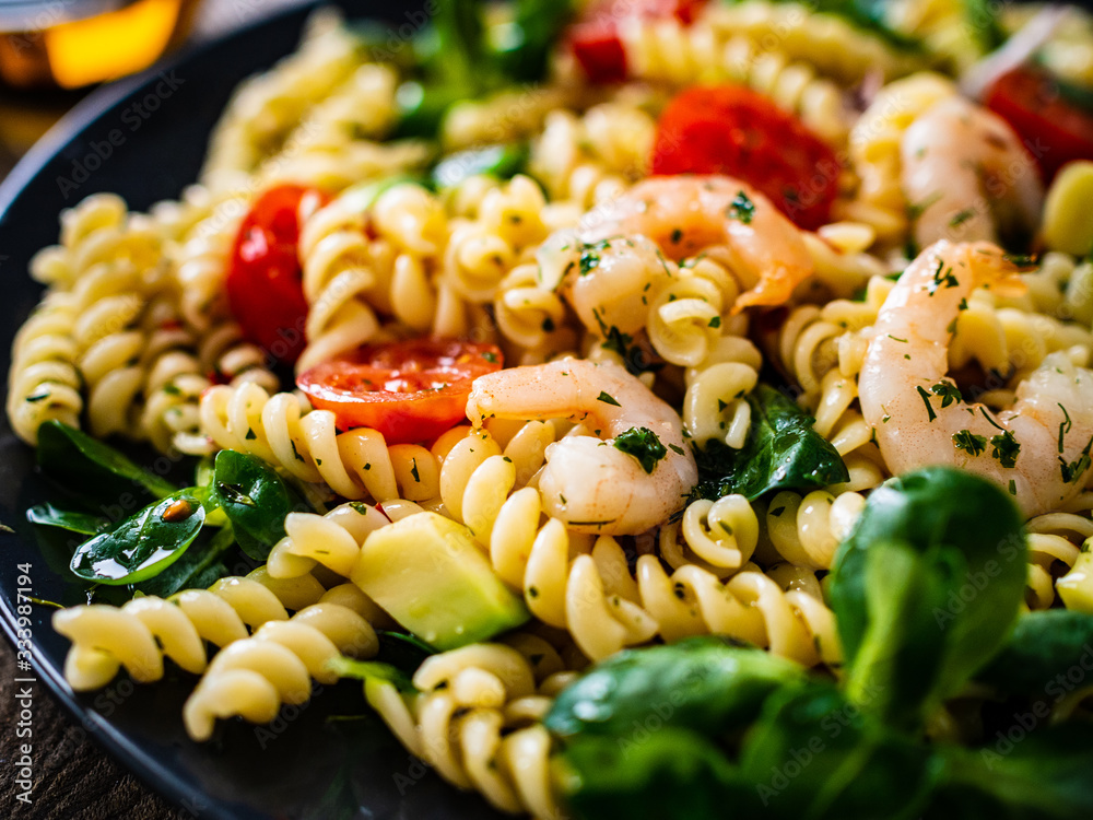 Pasta with prawns and vegetables on wooden background Pasta with prawns and vegetables on wooden background