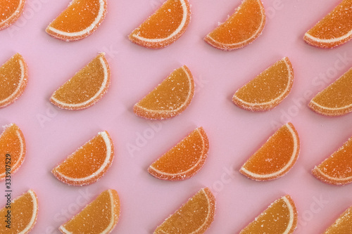 Marmalade slices of orange and lemon laid in oblique rows on a pink background