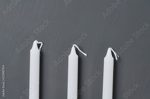 Roe of three long candles on dark concrete surface