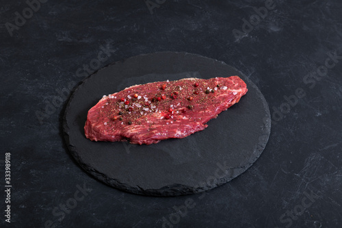 Raw fresh marbled meat and seasonings on dark background top view