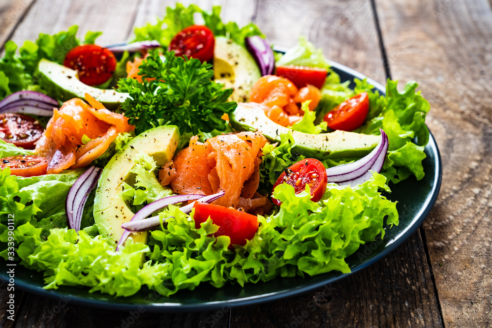 Salmon salad - smoked salmon and vegetables on wooden background