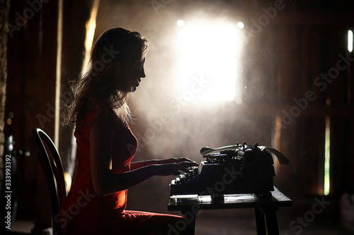 A girl in retro style prints on an old typewriter