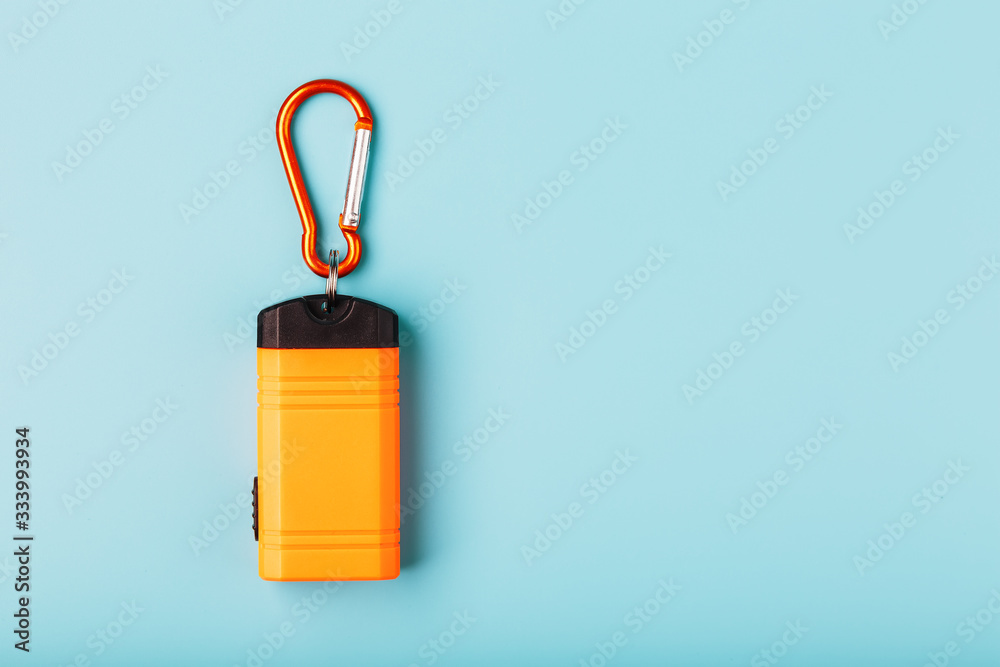 Orange led Flashlight with a carabiner on a blue background. LED lights in flight. Orange led Flashlight with a carabiner on a blue background. LED lights in flight.