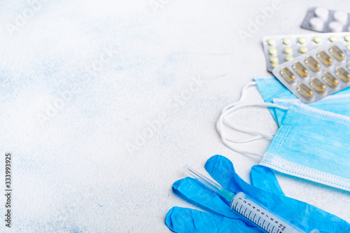 Medical protective masks, latex medical gloves, disposable syringe and pills on white background. The concept of protecting health from the virus.