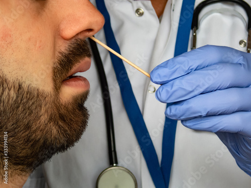 Quick test for suspected coronavirus diagnosis.  Physician taking a nasofaringeal sample of an adult bearded man, with a cotton swab. Covid19 screening. photo