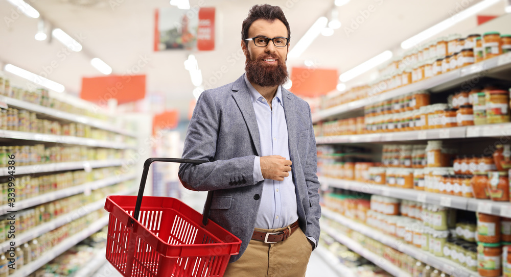 Bearded man holding a shopping basket inside a supermarket