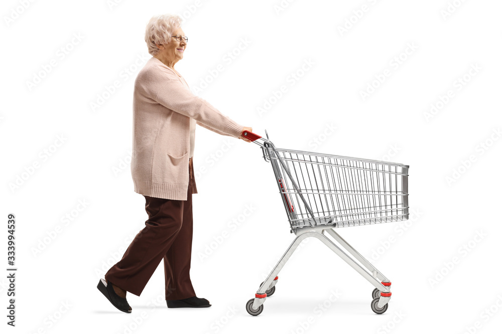 Senior lady walking and pushing an empty shopping cart Senior lady walking and pushing an empty shopping cart