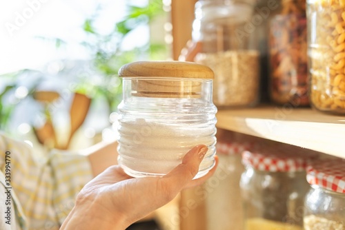 Cuadro en lienzo Food storage in pantry, woman holding jar of sugar in hand.
