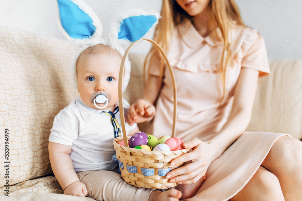 Happy Easter. A mother and a baby with rabbit ears on Easter day, with Easter colored eggs having fun. Family celebrates Easter Happy Easter. A mother and a baby with rabbit ears on Easter day, with Easter colored eggs having fun. Family celebrates Easter