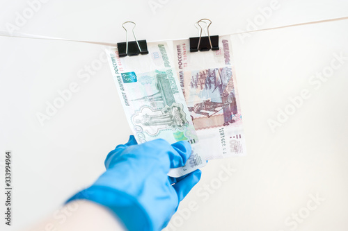 A hand in a blue rubber glove withdraws money from a clothes dryer.