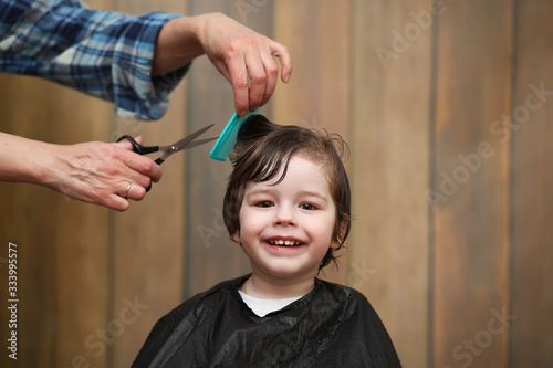 A little boy is trimmed in the hairdresser's bright emotions on face