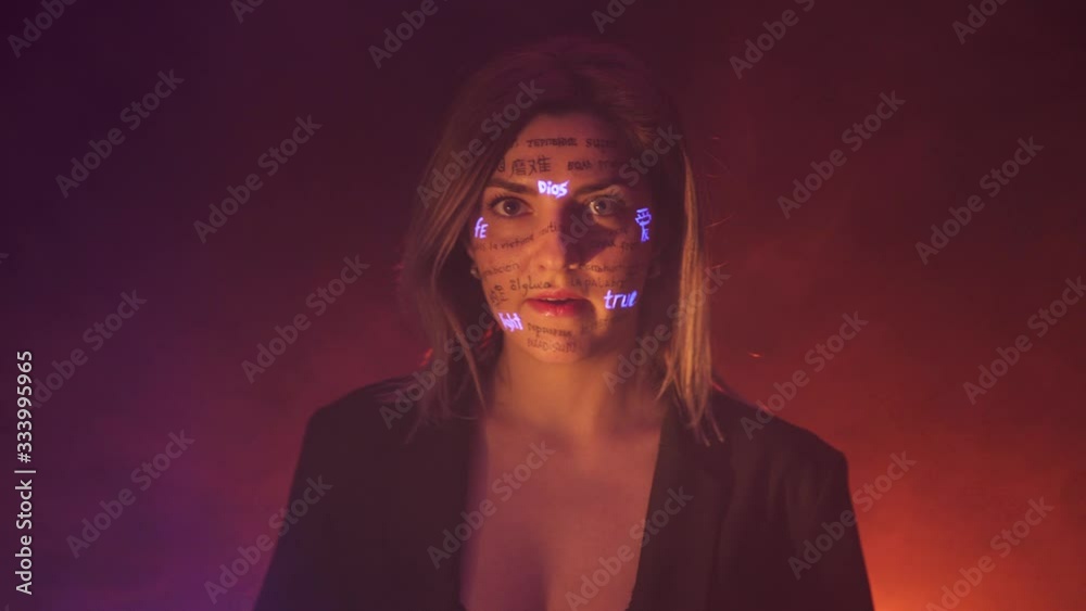 Girl in fog and Dramatic warm light with written different language words on her face. Beautiful model with UV Fluorescent neon creative make-up. face close up Girl in fog and Dramatic warm light with written different language words on her face. Beautiful model with UV Fluorescent neon creative make-up. face close up