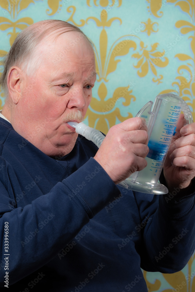 Elderly man using incentive spirometer for breath improvement. Helpful