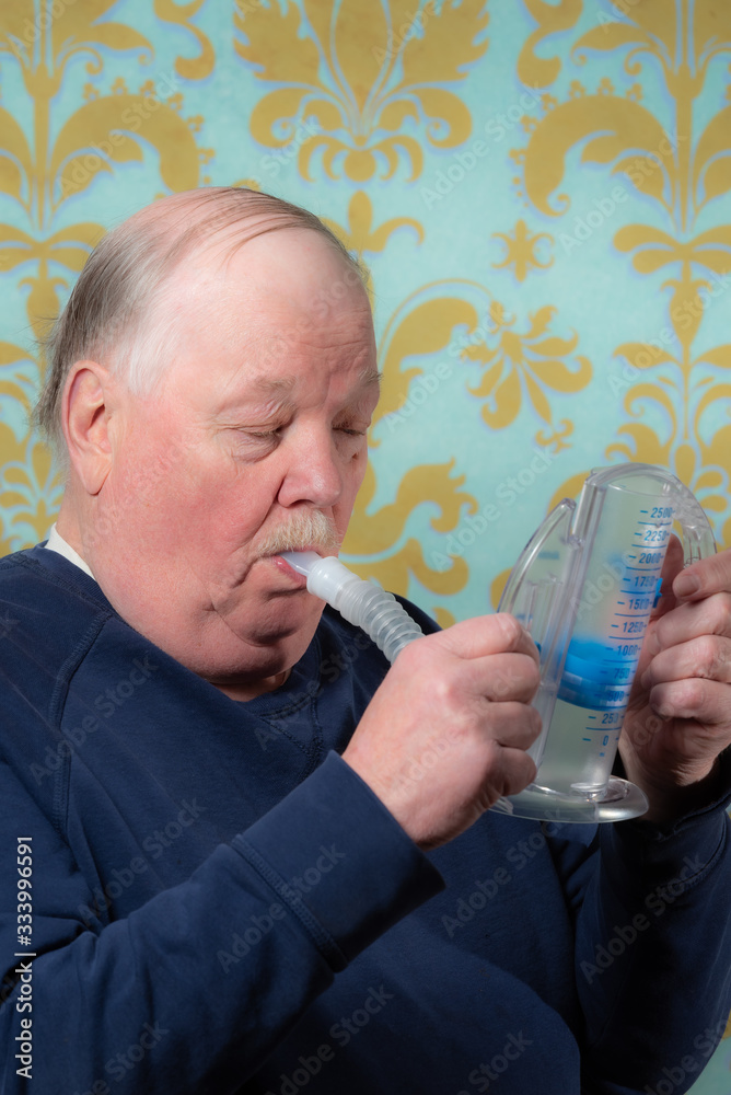 Elderly man using incentive spirometer for breath improvement. Helpful
