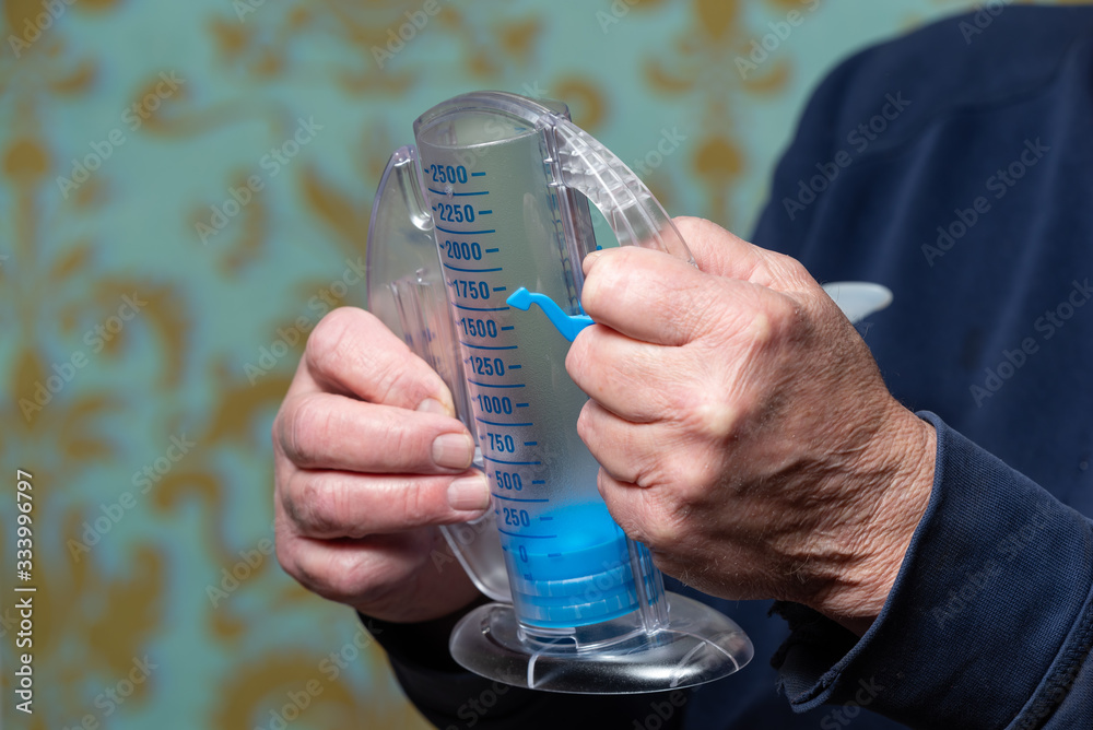 Elderly man using incentive spirometer for breath improvement. Helpful