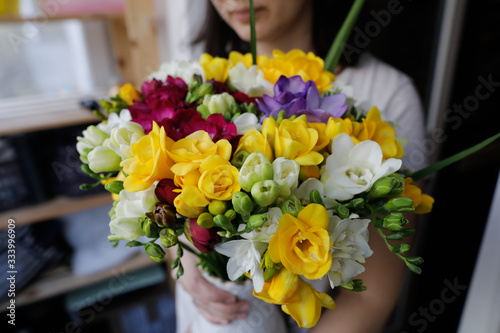 Shallow depth of field image (selective focus) with a woman holding a fresh bouquet of freesias.