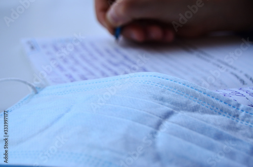 medical mask against the background of the child's hand which writes in a notebook photo