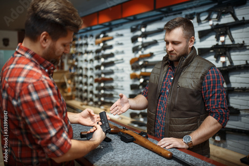 Man with owner choosing handgun in gun shop photo