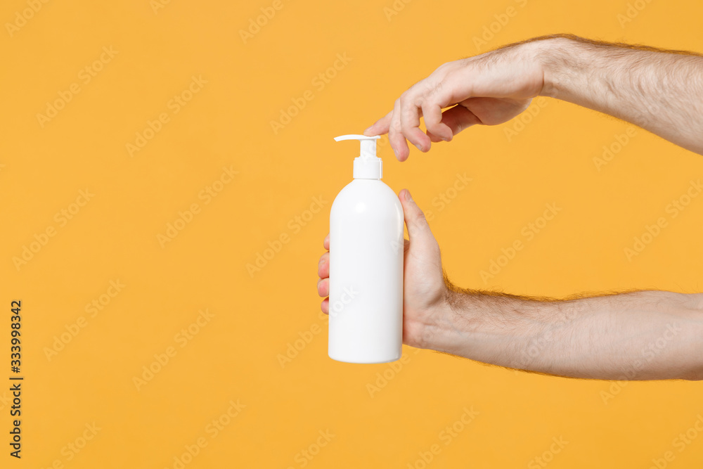 Close up cropped photo of male hold in hand bottle with antibacterial sanitizer soap isolated on yellow background. Epidemic pandemic coronavirus 2019-ncov sars covid-19 flu virus. Mock up copy space. - obrazy, fototapety, plakaty 