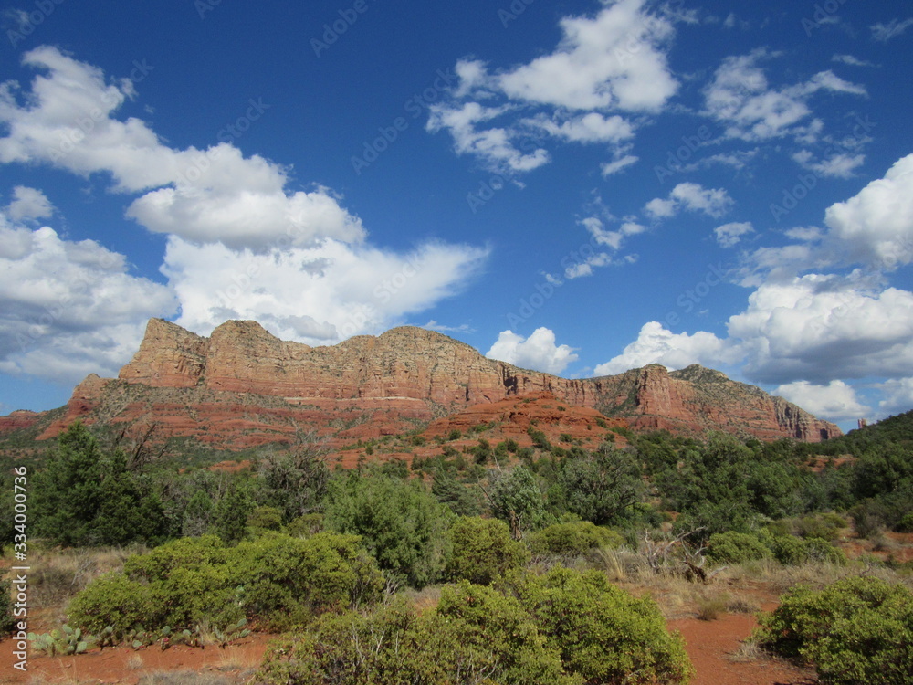 View of red rock mountains near Sedona, Arizona with clouds and blue sky in the background 