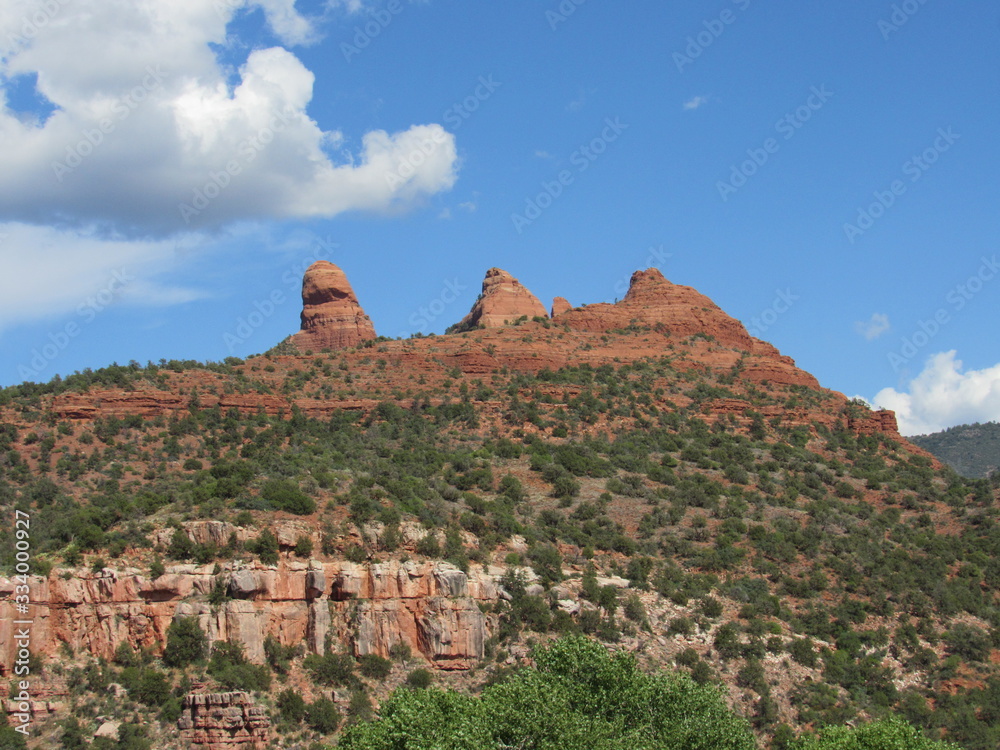 View of red rock mountains near Sedona, Arizona with clouds and blue sky in the background 