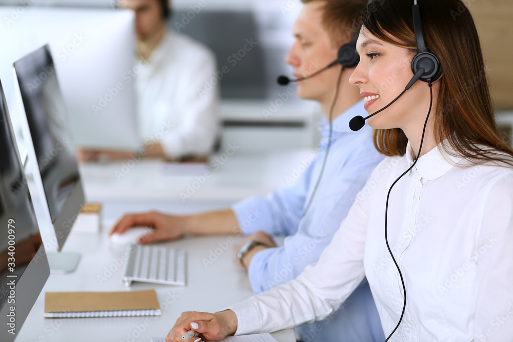 Call center. Group of diverse operators at work. Focus on beautiful asian woman in headset at customer service office. Business concept Call center. Group of diverse operators at work. Focus on beautiful asian woman in headset at customer service office. Business concept