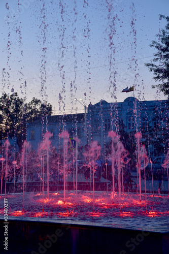 Fototapeta Naklejka Na Ścianę i Meble -  Beautiful fountains in the evening. Water jets are highlighted with bright colors, red, blue. Evening colors on the water create a romantic mood.