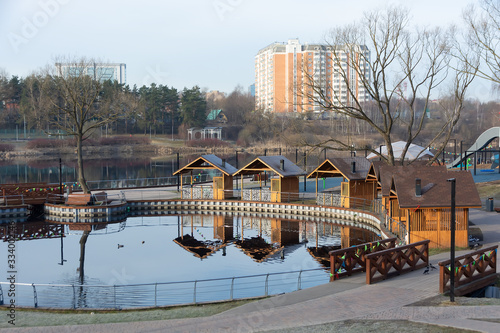 Panorama of small city park with pond  line of pavilions and bridge. Early spring morning