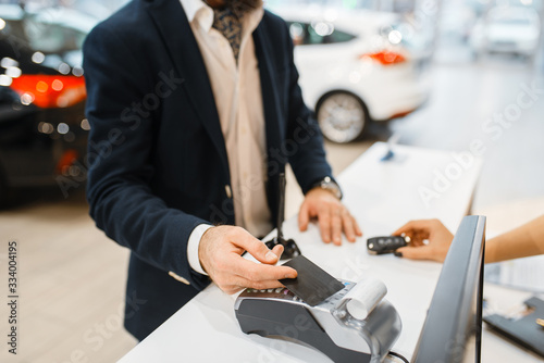 Slika na platnu Man pays for new auto in car dealership