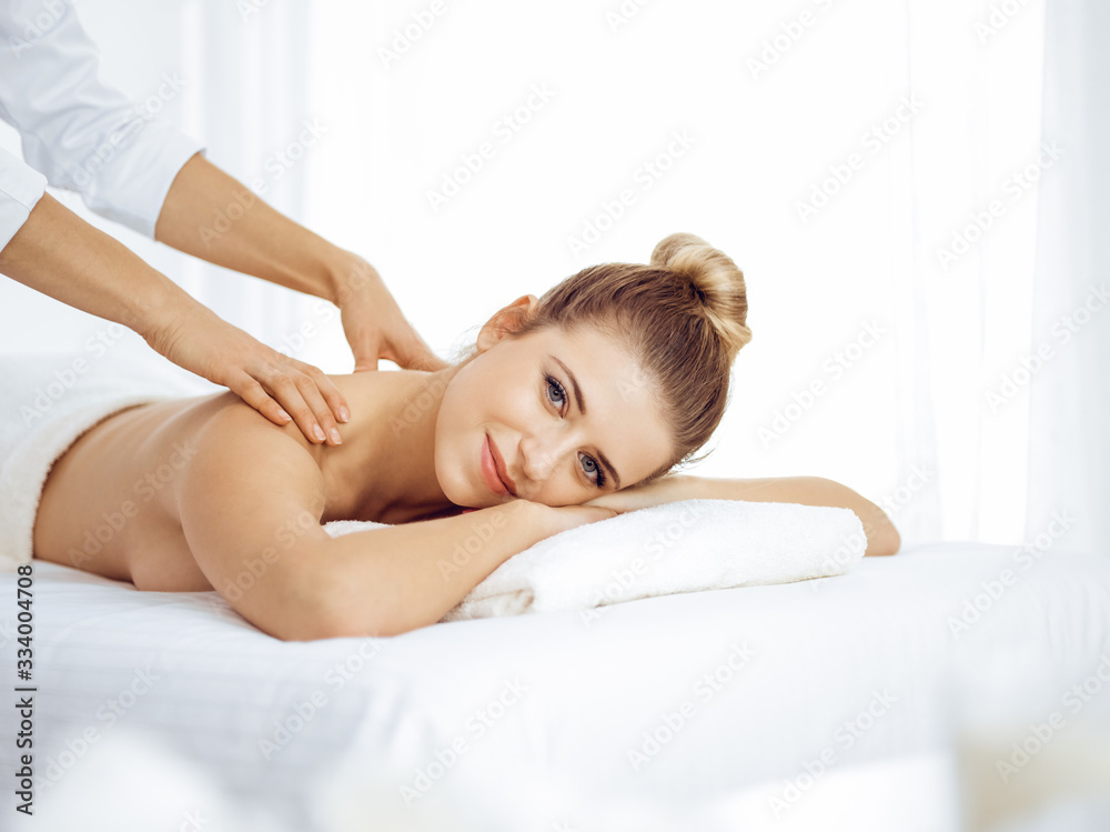 Young and blonde woman enjoying massage of back in spa salon. Beauty concept Young and blonde woman enjoying massage of back in spa salon. Beauty concept