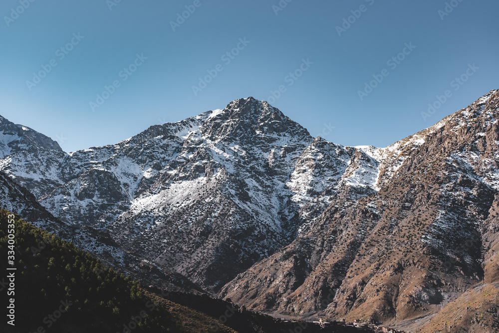 Snow covered peak of mount Toubkal in Morocco during spring on a sunny day. Atlas mountain range near Marrakesh. Start for hiking path.