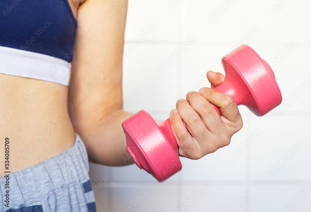 Girl holding a pink dumbbell. Hand, close-up Girl holding a pink dumbbell. Hand, close-up