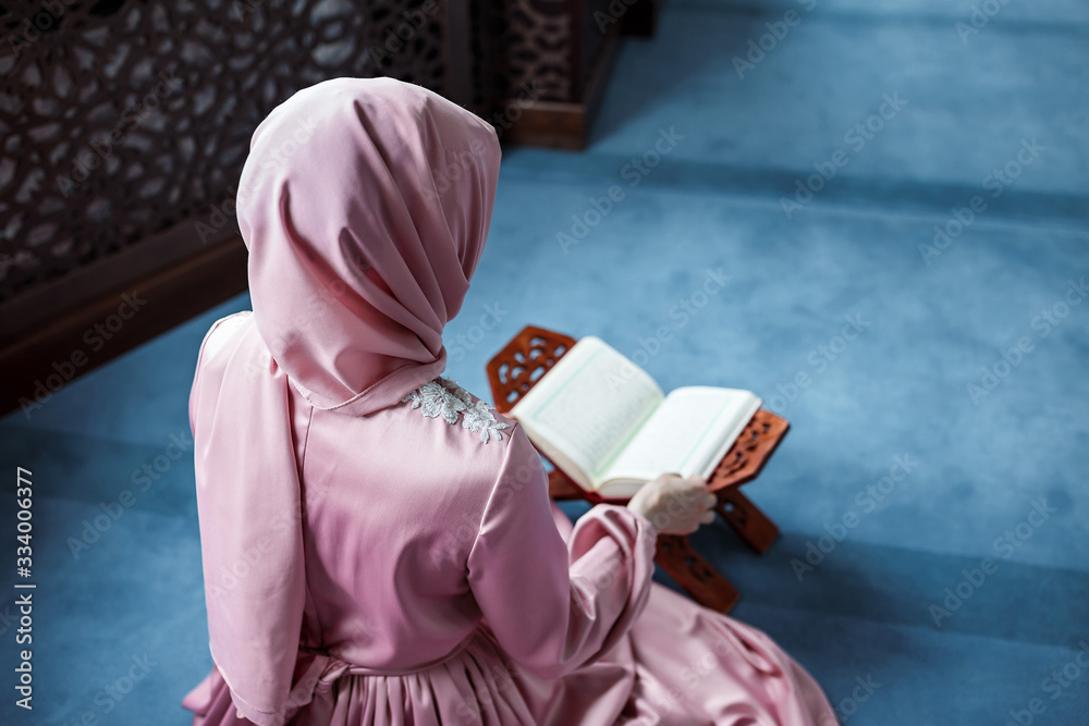 Woman praying in the mosque and reading the Quran