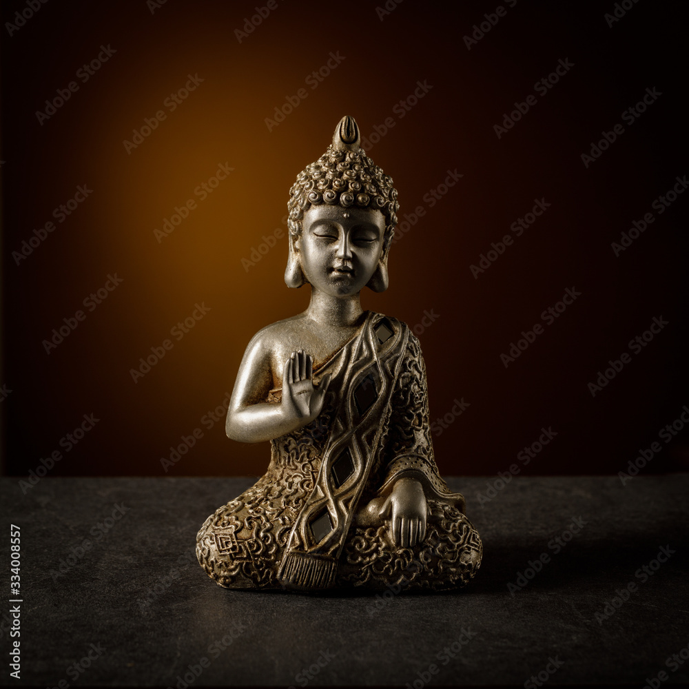 Old silver color statuette Buddha sitting in yoga pose.