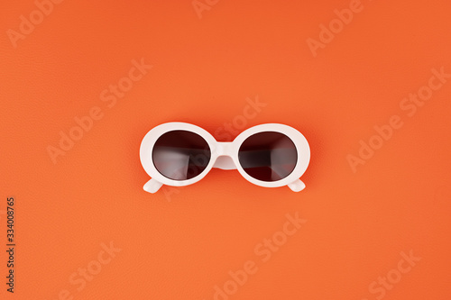 Stylish sunglasses over orange background. Summer fashion, party, summertime style, vacations concept. Minimal flat lay
