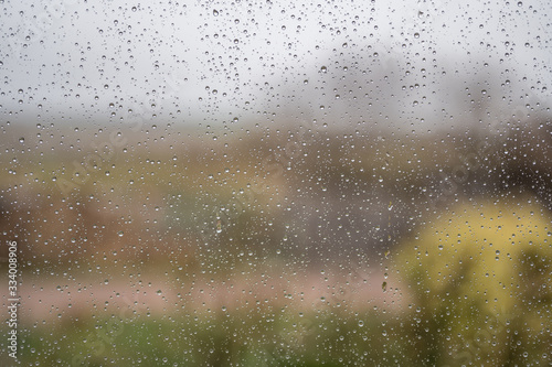 Regentropfen an der Fensterscheibe als melancholischer Hintergrund zum Thema Wetter und Depression