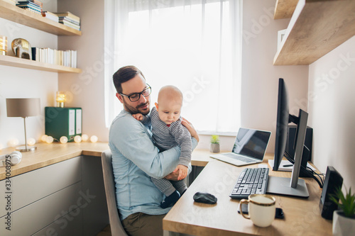 Wallpaper Mural Young father working from home and holding his baby boy. Torontodigital.ca