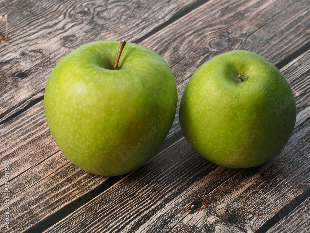 Two green apples on a wooden background