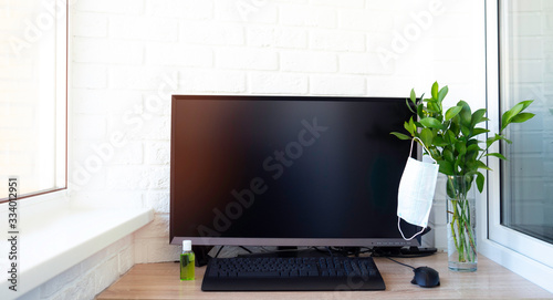 Working from home concept. Quarantine isolation because of coronavirus. Laptop computer, keyboard on wooden table. Face protective mask, disinfectant or sanitizer, cup of tea or coffee. Copy space.