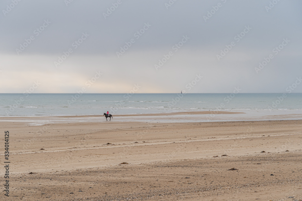 Agon-Coutainville, France - 12 30 2018: Rider on Pointe d'Agon Beach at Sunset