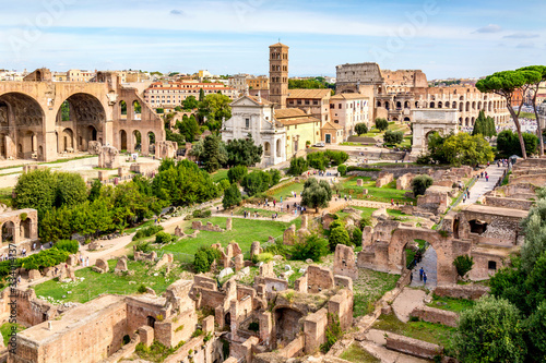 Aerial panoramic cityscape view of the Roman Forum and Roman Colosseum in Rome, Italy. World famous landmarks in Italy during summer sunny day.