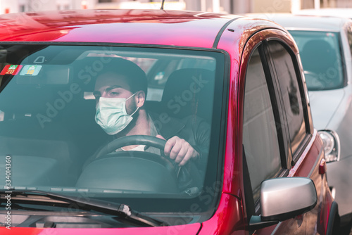 man with protective mask seated in car in traffic jam and looking ahead. - covid-19 corona crisis concept picture