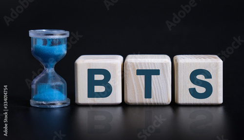 BTS concept with an hourglass. Wooden cubes on a black table photo