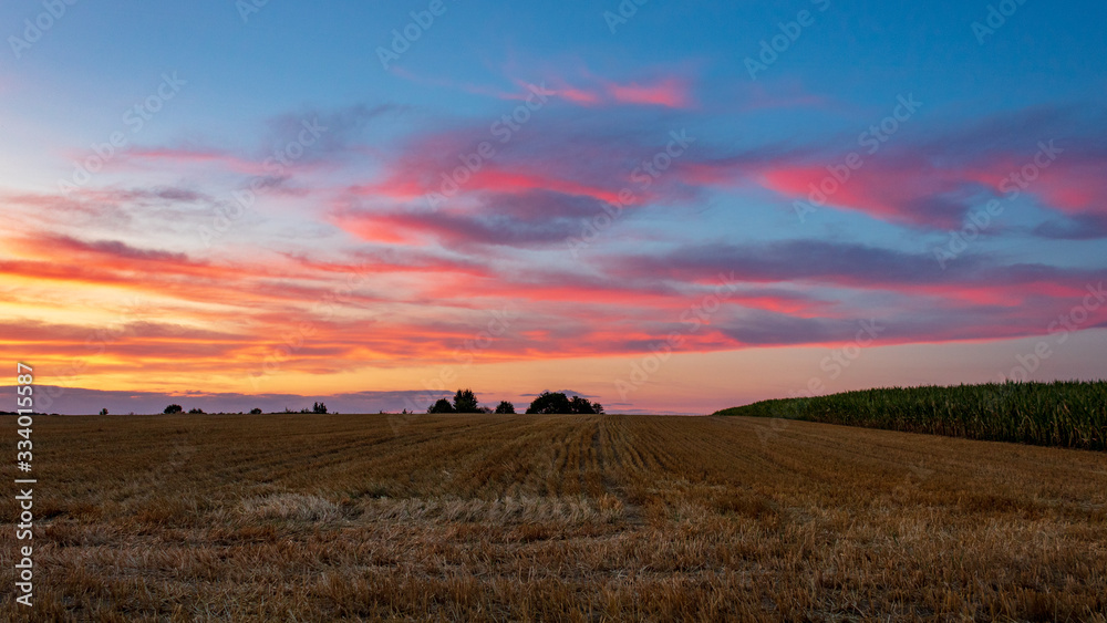 agricultural landscape with sunset sky and pink clouds in summer in Möckmühl, Germany.